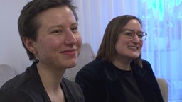 zwei junge Frauen sitzen nebeneinander