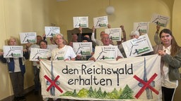 Eine Gruppe von Leuten mit Bannern und Plakaten: "Den Reichswald erhalten"