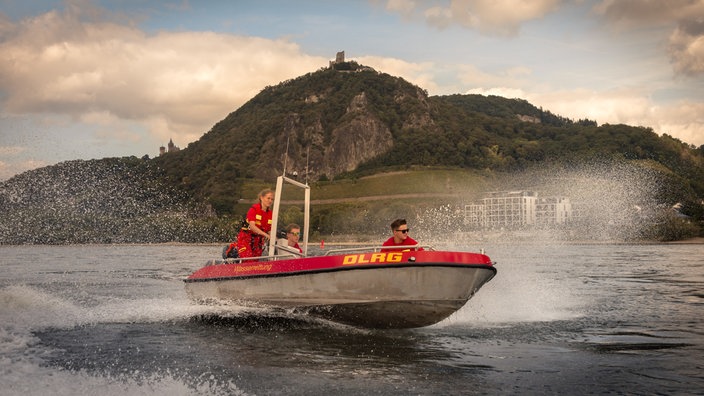 drei Menschen fahren auf einem Rettungsboot übers Wasser