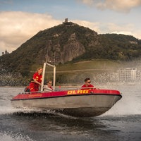 drei Menschen fahren auf einem Rettungsboot übers Wasser