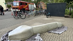 Eine Betonschlange liegt auf dem Schulhof. Noch ist sie grau, aber bald soll sie bunt bemalt werden. 