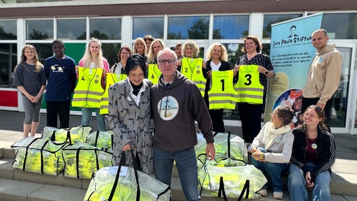 Mitglieder der Luis-Paulo-Stiftung und von der Schule lachen mit ihren Warnwesten in die Kamera