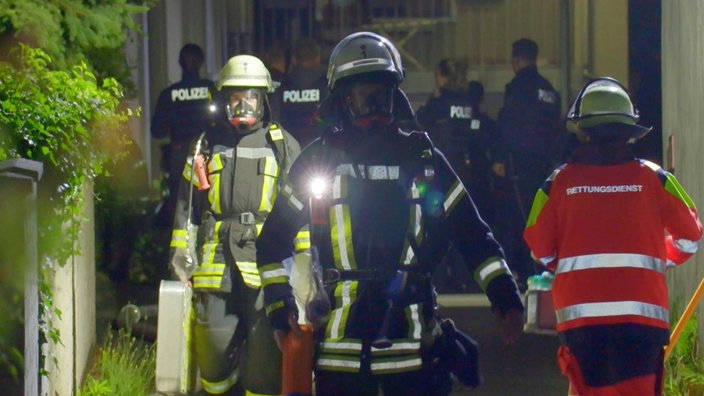 Feuerwehrleute und Rettungskräfte laufen in Haus