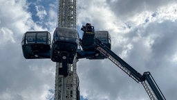 Ein Rettungskorb der Feuerwehr fährt in 30 Metern Höhe an ein Fahrgeschäft der Rheinkirmes Düsseldorf, 