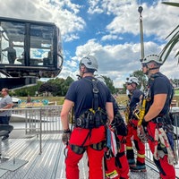 Mehrere Feuerwehrmänner der Höhenrettung stehen vor einem Fahrgeschäft auf der Düsseldorfer Rheinkirmes