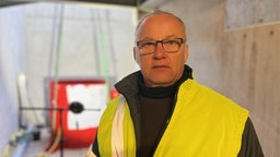 ein Mann trägt eine Brille und hat eine gelbe Warnjacke an