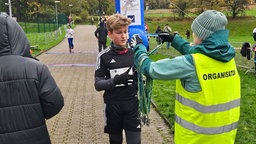 Ein Junge bekommt eine Teilnehmerehrung in Form eines Anhängers beim Röntgenlauf in Remscheid