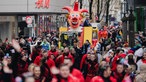 Ein großer Wagen ist mit einem Clowns-Kopf dekoriert. Darum herum stehen viele Menschen.