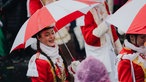 Ein Tanzmariechen mit rot-weißem Regenschirm. 