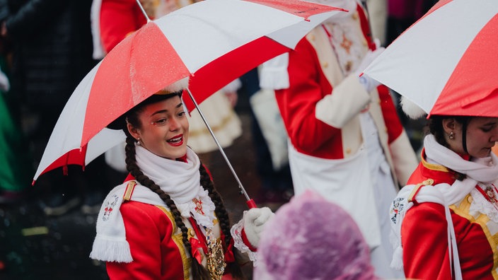 Ein Tanzmariechen mit rot-weißem Regenschirm. 