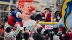 Eine Frau wirft Süßigkeiten von einem Themenwagen mit einem großen Papp-Clown.