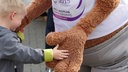 Eine Kinderhand berührt die Hand des Reit-WM-Maskottchens.