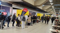 Menschen stehen in einer langen Schlange im Flughafen Köln/Bonn