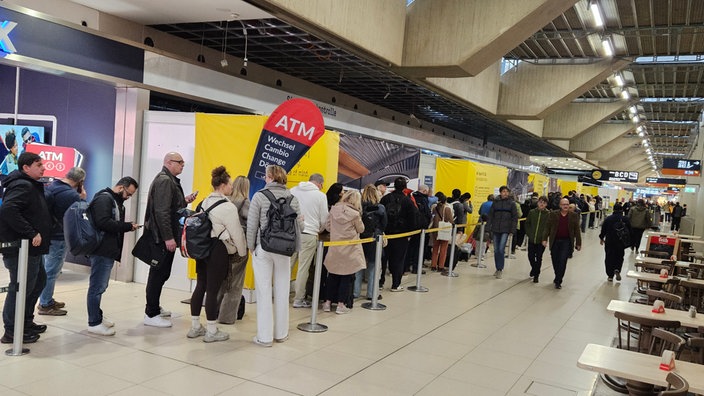 Menschen stehen in einer langen Schlange im Flughafen Köln/Bonn