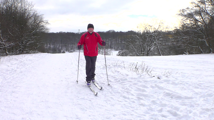 Mann mit Langlauf- Skirn fährt durch verschneite Winterlandschaft