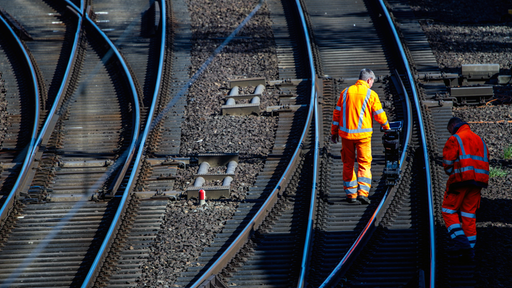 zwei Gleisbauarbeiter kontrollieren Bahnschienen