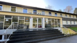 Ein gelbes Schulgebäude von außen.