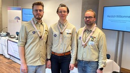 Auf dem Bild sind drei Menschen in braun-beiger Pfadfinder-Uniform zu sehen. Von links nach rechts: Sebastian Becker, Annkathrin Meyer, Maximilian Strozyk.