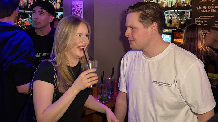 Zwei junge Menschen sind in einer Bar und unterhalten sich.
