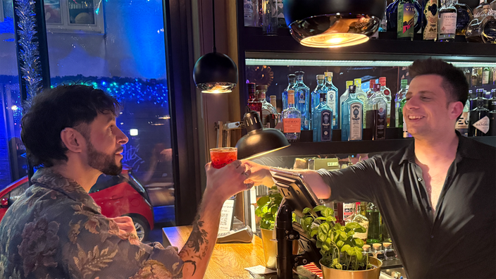 Ein Kellner überreicht einen Drink über die Theke.