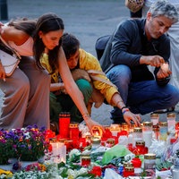 Auf dieser Aufnahme aus dem August 2024 ist zu sehen, wie mehrere Menschen knien und Kerzen abstellen