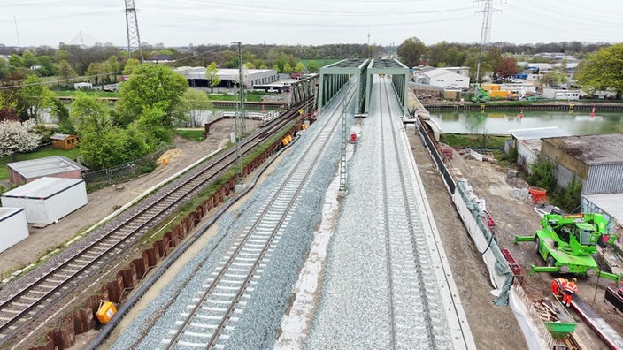 Zwei neue Bahngleise und neue Brücken über einen Kanal, an den Seiten wird noch gebaut