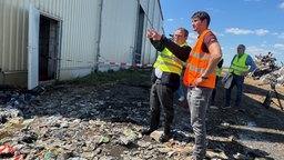 Betreiber Christian Hündgen mit NRW-Umweltminister Oliver Krischer bei der Begutachtung des Brandschadens