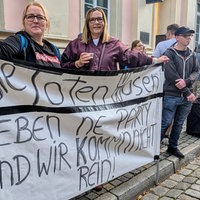 Anja und Susanne halten Banner zum Toten-Hosen-Konzert in Düsseldorf hoch. Darauf steht Die Toten Hosen geben ne Party und wir kommn nicht rein