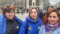 Drei Frauen auf der Dome. Zwei von ihnen Tragen Anstecker oder Symbole in den Farben der ukrainischen Flagge