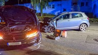 Zwei Autos stehen schwer beschädigt auf einer Straße bei Nacht