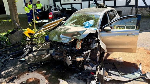 Der zertrümmerte Unfallwagen umgeben von abgesplittereten Autoteilen 
