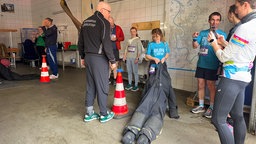 Emy Hetemi zieht auf der Feuerwehrwache eine Puppe beim Urban Trail in Düsseldorf