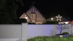 Ein Haus vor dem eine kleine Mauer steht. Es ist Nacht. 