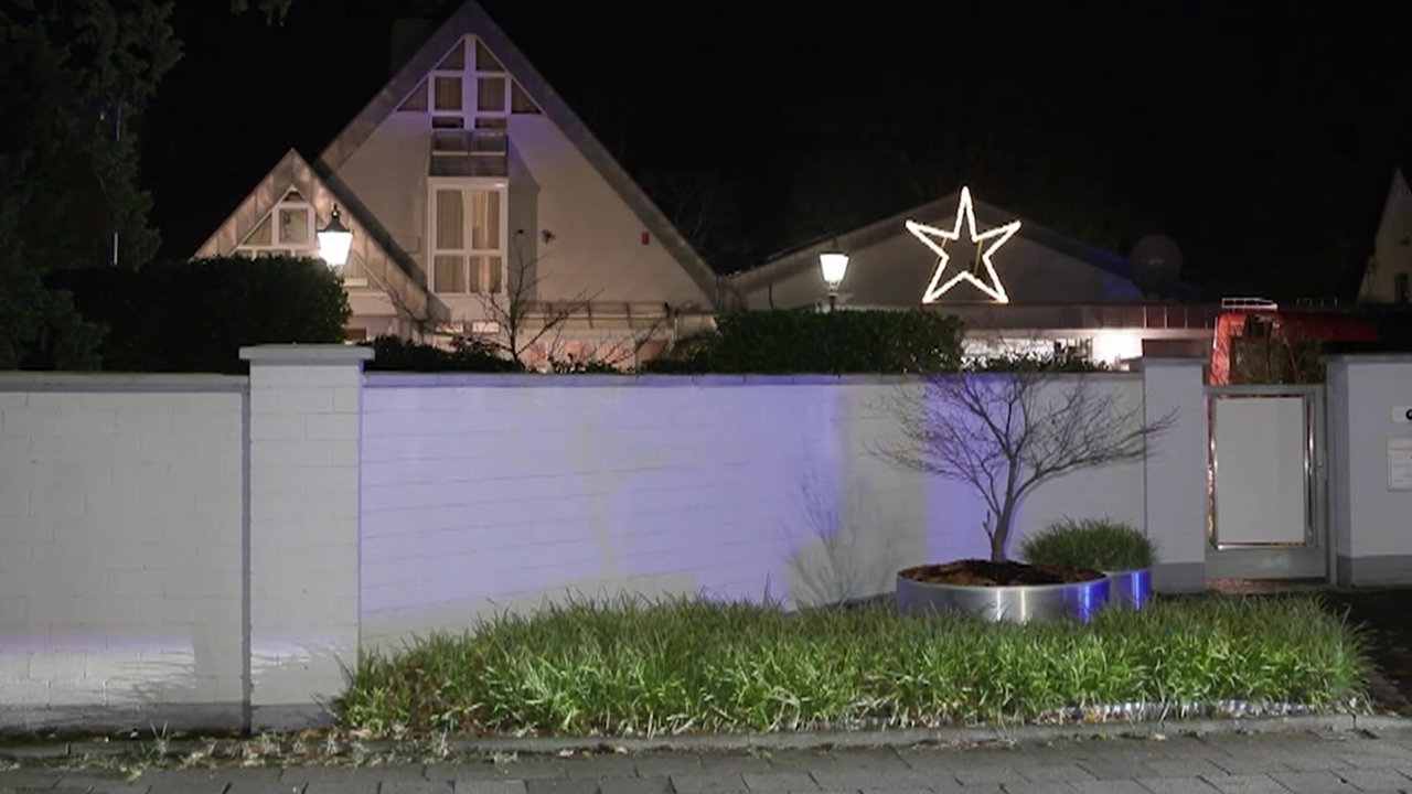 Ein Haus vor dem eine kleine Mauer steht. Es ist Nacht. 