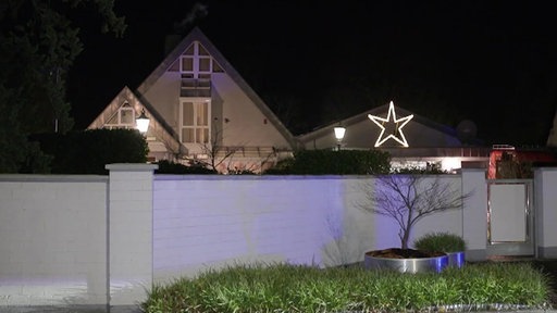 Ein Haus vor dem eine kleine Mauer steht. Es ist Nacht. 