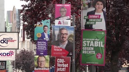 Mehrere Wahlplakate hängen nah beieinander