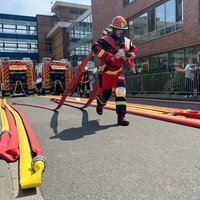Ein Feuerwehrmann zieht zwei Schläuche, die auf seinen Schultern liegen