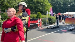 Eine Feuerwehrfrau in voller Ausrüstung zieht eine Puppe 