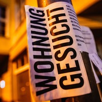 Ein Zettel mit der Aufschrift "Wohnung gesucht" hängt an einer Laterne