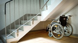 Ein Rollstuhl steht unter einer Treppe