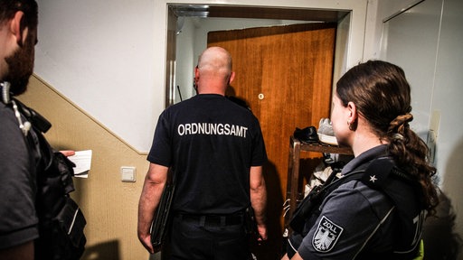 Mitarbeitende des Ordnungsamts und des Zolls stehen vor einer offenen Tür.