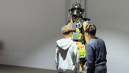 Zwei Jungen begutachten einen Schutzanzug der Feuerwehr