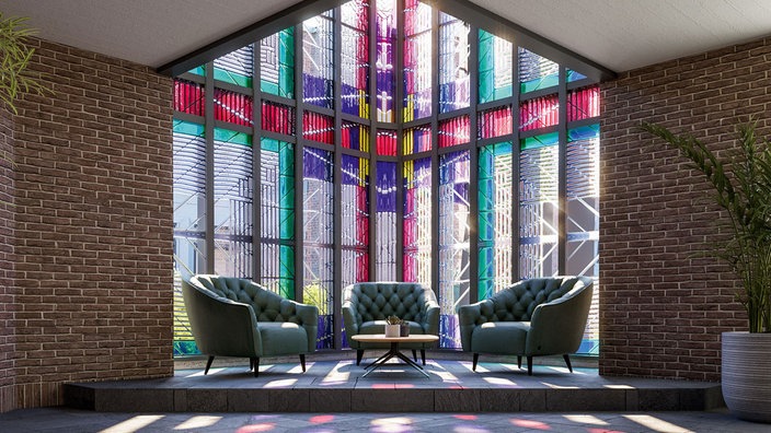 Auf dem Foto ist ein Tisch mit modernen Sesseln, dahinter sind Kirchenfenster.