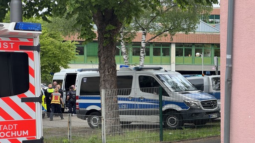 Vor der Rupert-Neudeck-Schule in Bochum stehen Einsatzfahrzeuge der Polizei und ein Rettungswagen. An der Schule hat es einen Amokalarm gegeben.