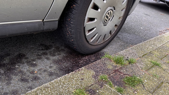 Rote Flüssigkeit auf dem Asphalt unter einem Autoreifen