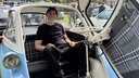 Ein Mann sitzt lächelnd in seiner BMW Isetta von 1958. 