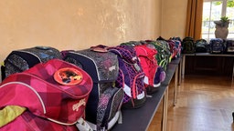 Schul-Tornister sind auf Tischen aufgereiht