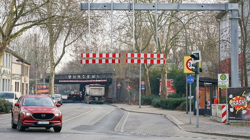 Im Hintergrund ist ein Brücke mit Höhenbeschränkung zu sehen, unter der ein Lkw durchfährt