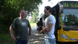 Schüler Aleksandar Markovic mit dem 64-Jährigen Busfahrer. Sie stehen nebeneinander vor dem Bus.