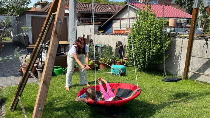Eine Mutter mit ihren Kindern im Garten.